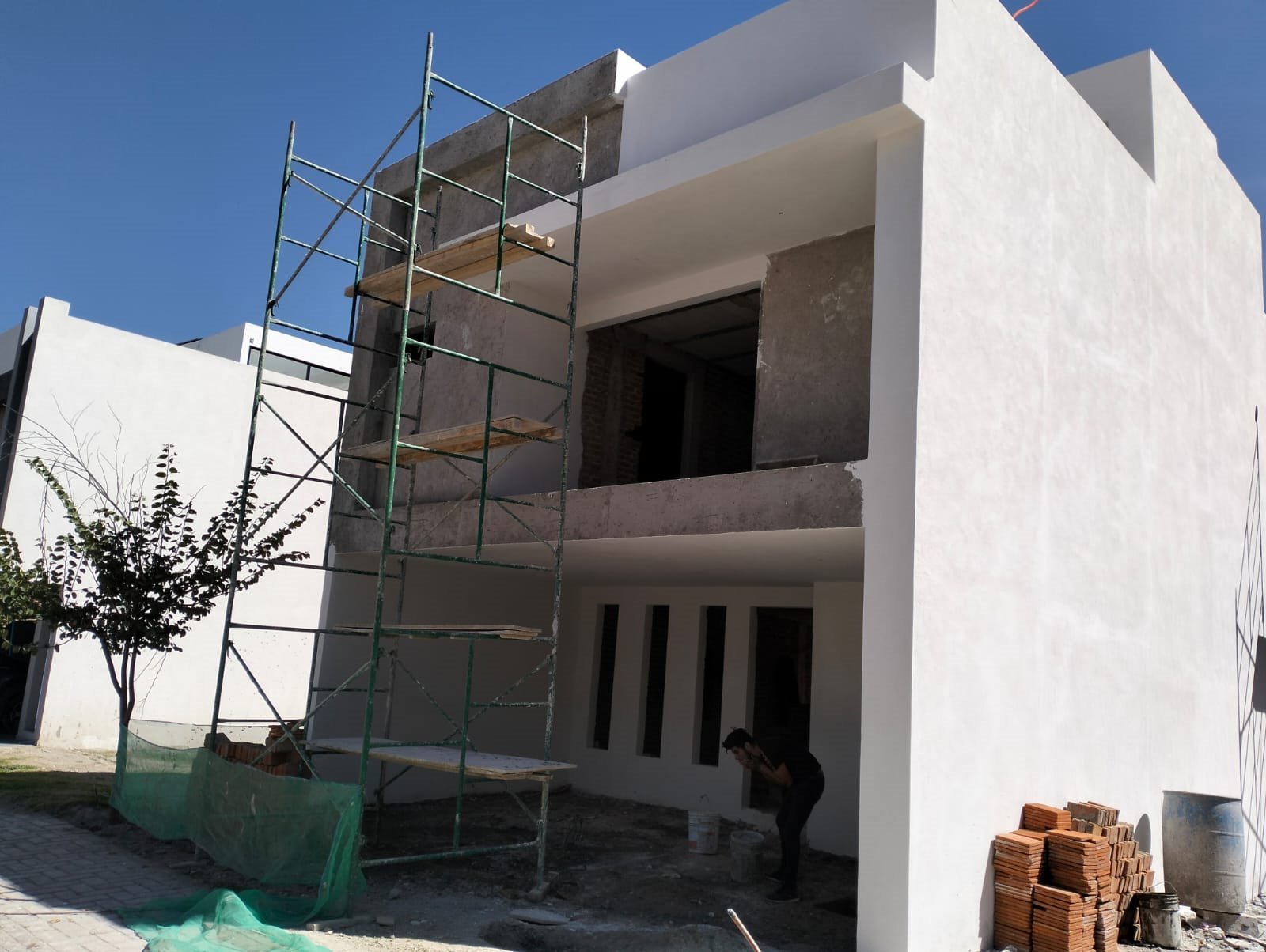 Fachada con andamio, aplanado en proceso, otro ángulo
